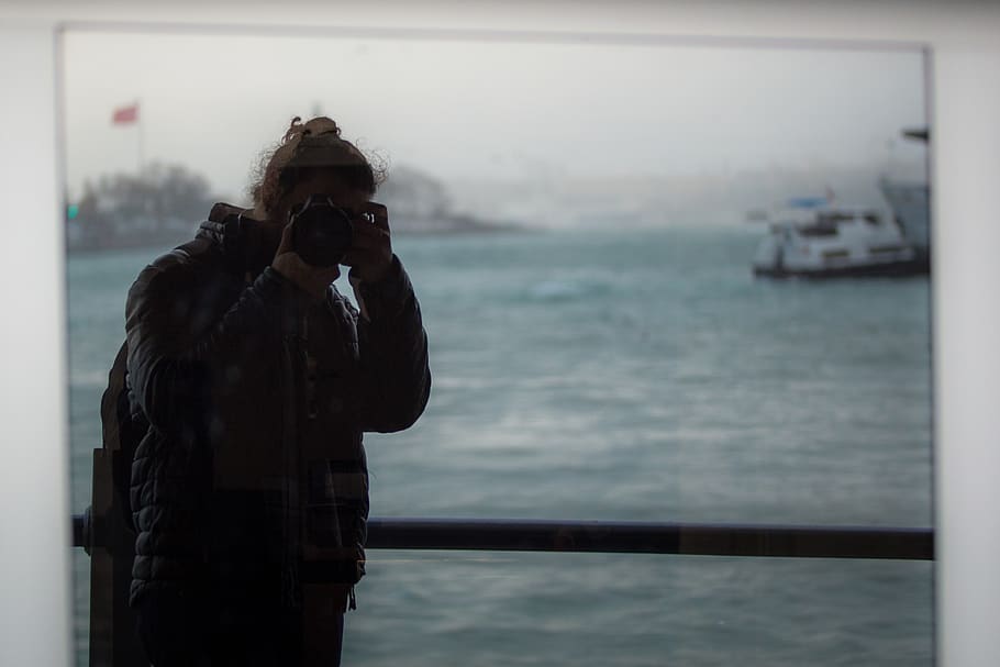 Mann, der Kamera hält, Transport, Fahrzeug, Boot, Mensch, Person, Fotograf, Fotografie, Foto, Jacke, Mantel, Kleidung, bekleidung, Gesicht, Porträt, Fernglas, Brücke, Promenade, Gebäude, Musiker, Musikinstrument, eine Person, Fotografie-Themen, echte Menschen, Technologie, Fotografieren, Stehen, Kamera - Fotoausrüstung, Wasser, Transportmittel, Taille hoch, halten, Freizeitbeschäftigung, Meer, Wasserfahrzeug, Lebensstile, Fokus auf den Vordergrund, Fotoausrüstung, draußen, Digitalkamera, warme Kleidung, 2K