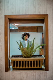 planta de fulla verda, decoració de la llar, persona, humà, planta, prestatge, sòls, pantalla lcd, electrònica, pantalla, monitor, mobles, fusta, jar, planta en test, ceràmica, gerro, flor, llar de foc, una persona, a l'interior, vista frontal, estils de vida, persones reals, adult, retrat, dones, de peu, la vida domèstica, material de fusta, mirant, activitat d'oci, finestra, interior de casa, vidre - material, mirant la càmera, pentinat, femelles, 5K, CC0, domini públic, lliure de regalies