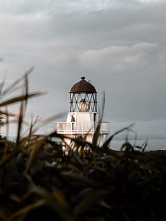 person, standing, lighthouse, grass, perspective, cloud - sky, sky, nature, plant, day, beauty in nature, land, built structure, architecture, outdoors, selective focus, field, no people, non-urban scene, focus on background, tower, lifestyles, tranquility, 4K, CC0, public domain, royalty free