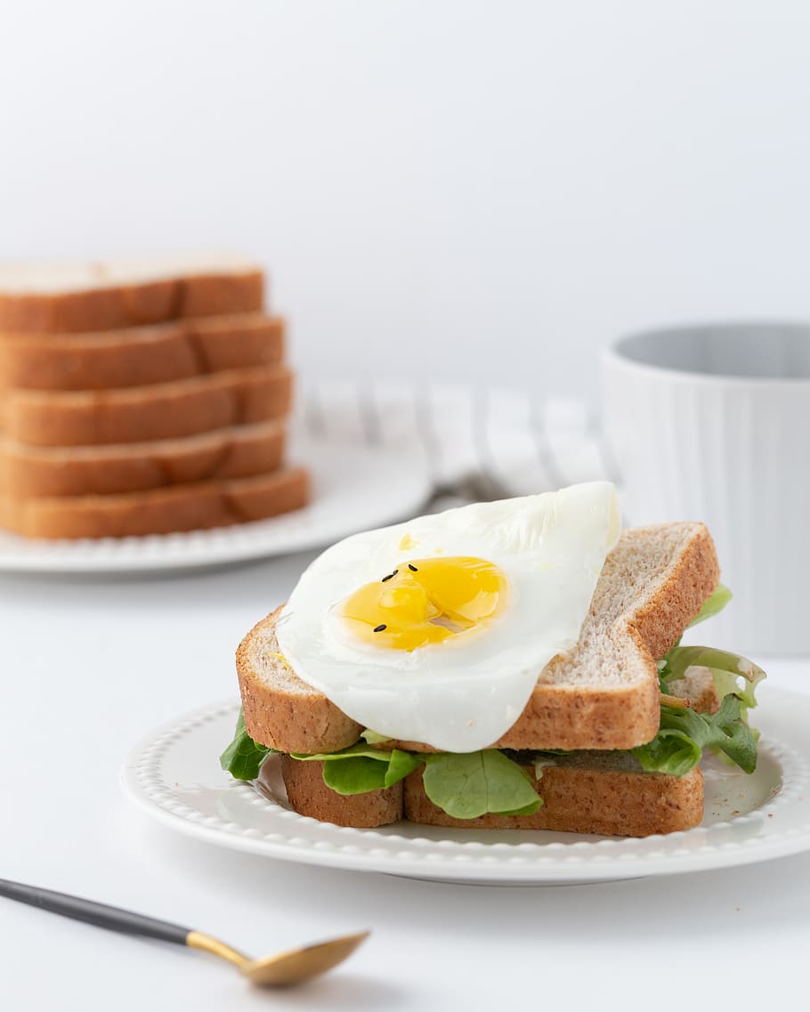 Blattgemüse, Brot, Ei, Lebensmittel, Essen und Trinken, Teller, fertig für den Verzehr, Frische, Mahlzeit, drinnen, keine Leute, gesundes Essen, Frühstück, Tabelle, Stillleben, Nahansicht, Spiegelei, Wohlbefinden, Fokus auf den Vordergrund, Eigelb, Genuss, gebraten, Sonnenseite nach oben, Snack, Versuchung, Vollkornbrot, 2K