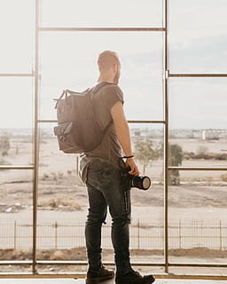 mochila cinza dos homens, uma pessoa, janela, de pé, dia, homens, roupa casual, pessoas reais, arquitetura, vidro - material, visão traseira, ao ar livre, comprimento total, natureza, estrutura construída, machos, transparente, adulto jovem, esperando, contemplação, 4K, CC0, domínio público, royalty free