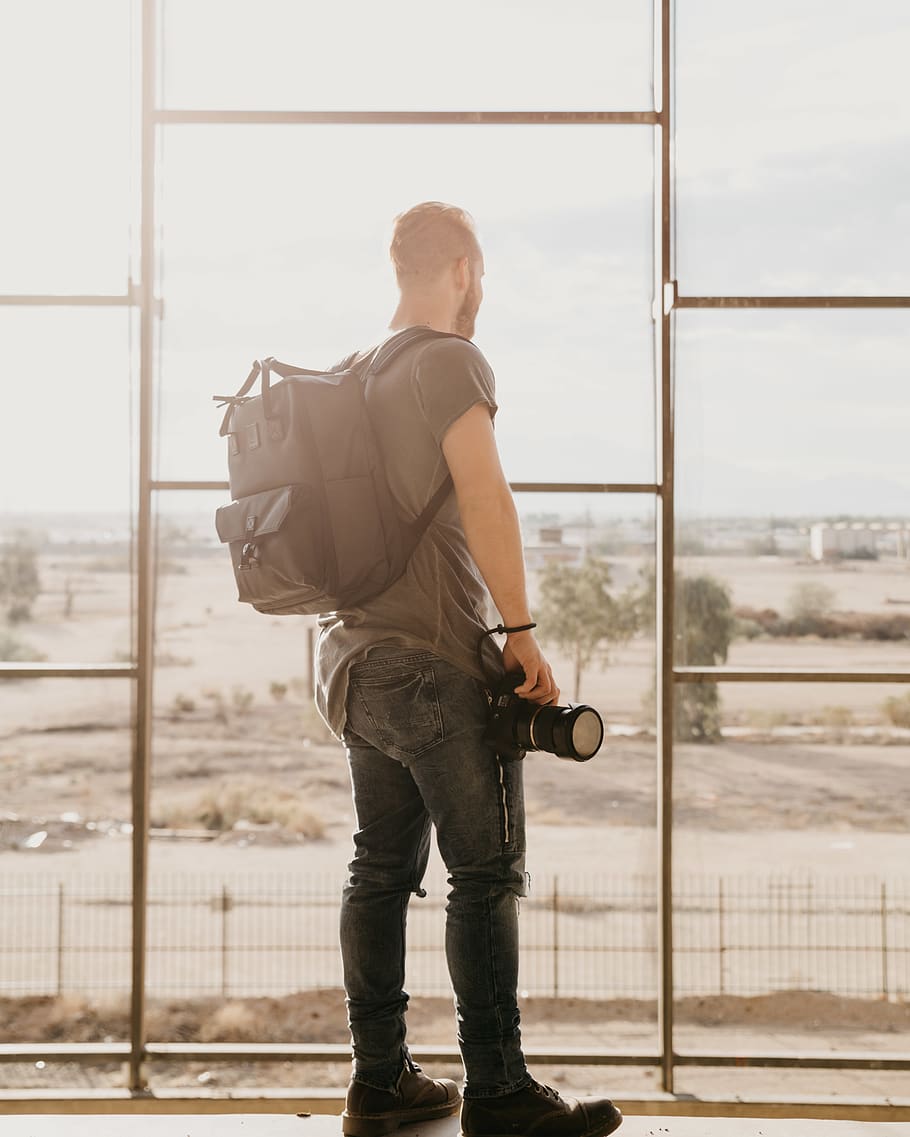 mochila cinza dos homens, uma pessoa, janela, de pé, dia, homens, roupa casual, pessoas reais, arquitetura, vidro - material, visão traseira, ao ar livre, comprimento total, natureza, estrutura construída, machos, transparente, adulto jovem, esperando, contemplação, 4K