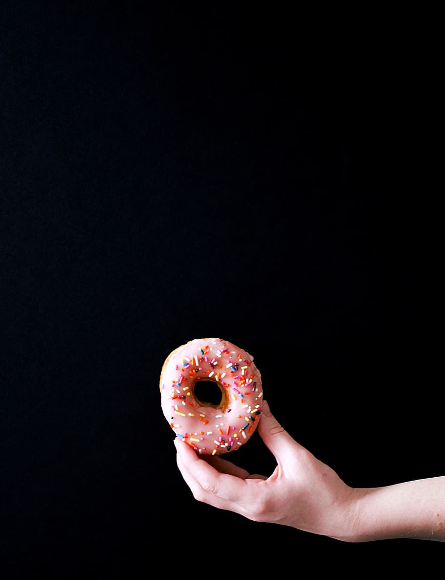 rosa Donut, schwarzer Hintergrund, Essen und Trinken, Lebensmittel, menschliche Hand, halten, kopieren sie platz, menschliches Körperteil, eine Person, drinnen, Hand, Studioaufnahme, Frische, Nahansicht, gebacken, Süßes Essen, fertig für den Verzehr, menschlicher Finger, Krapfen, Cupcake, Finger, Versuchung, 2K
