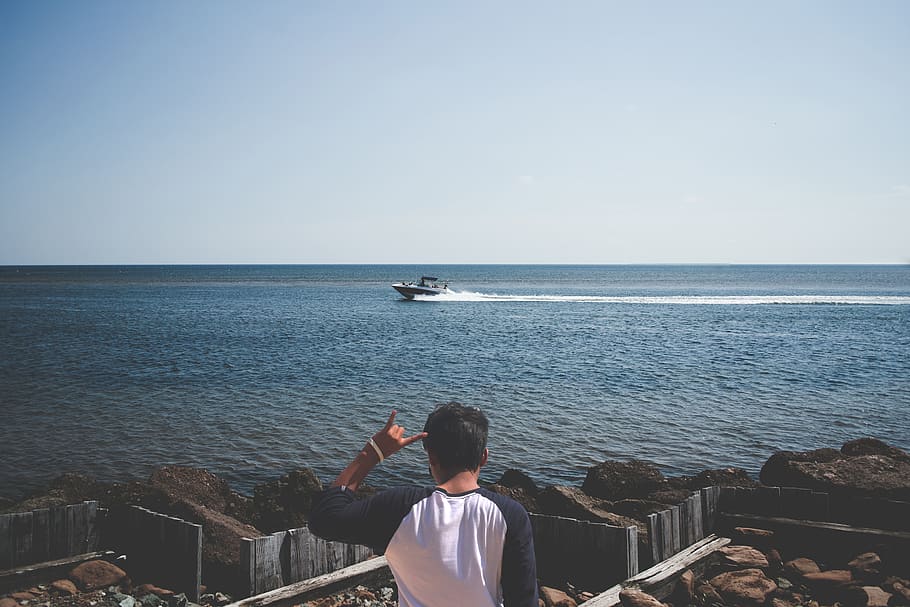 Mann, tragen, Blau, Weiß, T-Shirt, Nächster, Strand, Boot, Geste, Kerl, Ozean, Person, Meer, Ufer, Schnellboot, winken, echte Menschen, Wasser, Horizont über Wasser, Himmel, Szenen - Natur, Horizont, Freizeitbeschäftigung, Rückansicht, Lebensstile, eine Person, Schönheit in der Natur, klarer Himmel, Männer, Natur, Tag, idyllisch, ruhige Szene, draußen, 4K
