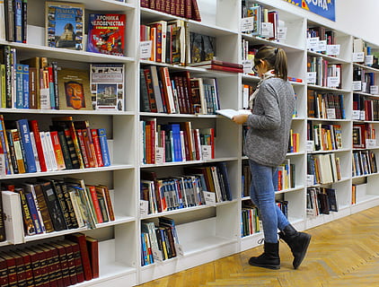vrouw leesboek, archief, mooi, stapel boeken, boekenkast, boeken, boekenkasten, boekenwinkel, keuze, verzameling, college, opleiding, encyclopedie, meisje, binnenshuis, kennis, leren, aan het leren, bibliotheek, literatuur, roman, openbaar, lezen, lezing, Onderzoek, school-, plank, schappen, student, studie, aan het studeren, Universiteit, wijsheid, publicatie, boek, boekenplank, een persoon, volledige lengte, volwassen, vrouw, levensstijlen, staand, vrijetijdsbesteding, casual kleding, jonge volwassene, klant, bestellen, kapsel, gangpad, jeans, 4K