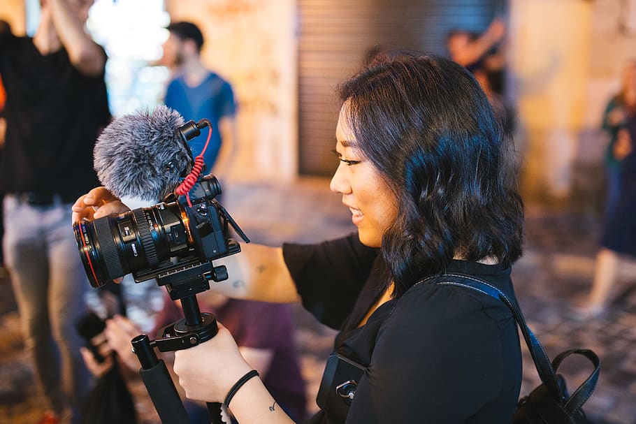 somrient, dona, celebració, negre, càmera dslr, càmera, equipament, periodista, lent, micròfon, gent, fotògraf, recreació, carrer, tecnologia, videògraf, vlog, vlogger, temes de fotografia, càmera de televisió, càmera - equip fotogràfic, ocupació, dones, rodatge, operador de càmera, cultura i entreteniment artístic, adult, els mitjans de comunicació, treball, ocupació professional, adult jove, activitat, industria del cinema, dones joves, fotografiar, grup de persones, càmera slr, 2K