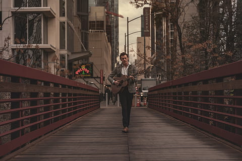 Mann, spielen, Gitarre, Steg, die Architektur, Brücke, Gebäude, Stadt, Tageslicht, Unterhaltung, Gitarrist, Kerl, Instrument, männlich, männliches Model, Musik-, Musikinstrument, Musiker, Künstler, Person, Straße, Straßenmusiker, Strassenfotografie, Saiteninstrument, tragen, eine Person, gebaute Struktur, in voller Länge, echte Menschen, Freizeitbeschäftigung, junger Erwachsener, Lebensstile, Legere Kleidung, Geländer, Stehen, Gebäudehülle, Vorderansicht, halten, junge Frau, der Weg nach vorn, Fußweg, Erwachsene, draußen, 8K, CC0, gemeinfrei, lizenzfrei