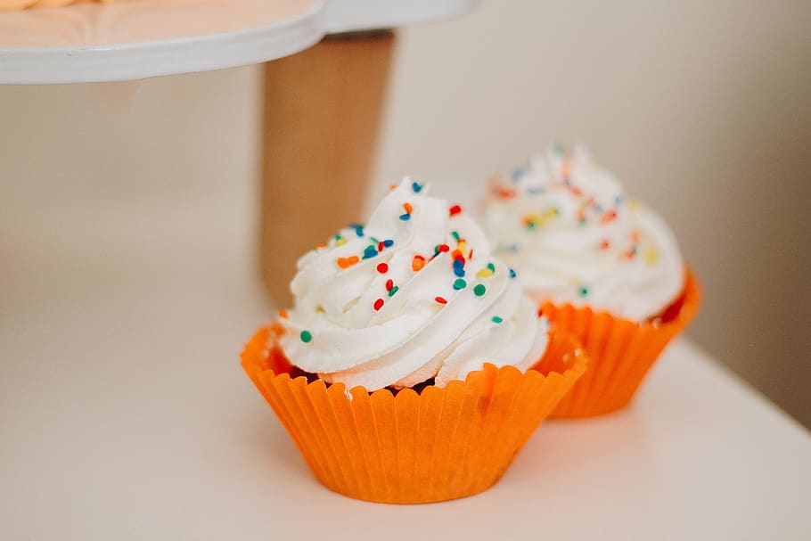 zwei Vanille Cupcake, Cupcake, Süss, Süßes Essen, Kuchen, Essen und Trinken, Genuss, Dessert, Lebensmittel, gebacken, Versuchung, drinnen, Sträusel, Glasur, ungesunde Ernährung, Frische, Fokus auf den Vordergrund, Nahansicht, Gruppe von Objekten, Cupcake-Halter, selektiver Fokus, Snack, 4K