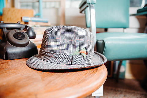 gray, fedora hat, table, clothing, apparel, hat, wood, sun hat, furniture, electronics, plywood, cowboy hat, desk, hardwood, brick, phone, display, screen, monitor, sombrero, couch, flagstone, indoors, wood - material, focus on foreground, no people, close-up, technology, still life, sewing machine, absence, seat, day, textile, pattern, fashion, thread, 5K, CC0, public domain, royalty free