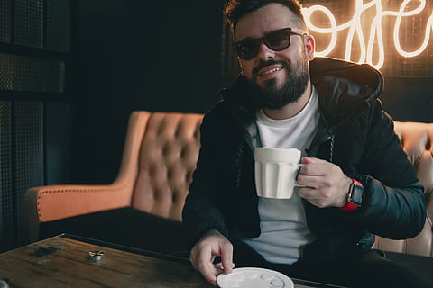 man, drinking, coffee, cafe, cappucino, espresso, sunglasses, seat, couch, neon, light, smile, happy, drink, food and drink, cup, men, leisure activity, refreshment, mug, young adult, sitting, coffee cup, facial hair, young men, adult, beard, casual clothing, coffee - drink, males, fashion, hipster - person, 4K, CC0, public domain, royalty free