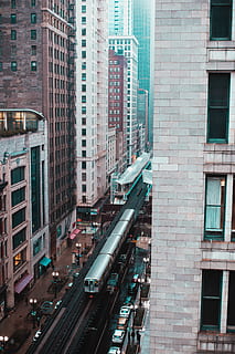 train between buildings, aerial shot, architecture, bird's eye view, buildings, city, downtown, from above, train, train station, transportation system, travel, urban, building exterior, built structure, building, motor vehicle, transportation, car, mode of transportation, land vehicle, street, day, office building exterior, high angle view, road, no people, modern, office, residential district, city life, skyscraper, outdoors, 5K, CC0, public domain, royalty free