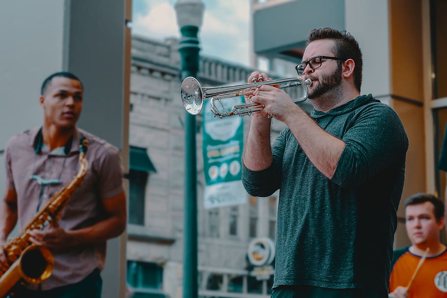 home, jugant, instrument de vent, adult, artista, banda, busking, concert, entreteniment, ulleres, pèl facial, Festival, jazz, homes, música, musical, instruments musicals, músics, a l'aire lliure, gent, rendiment, intèrprets, recreació, cançó, so, intèrpret de carrer, trompeta, desgast, instrument musical, celebració, cultura i entreteniment artístic, roba casual, persones reals, músic, estils de vida, home jove, adult jove, centrar-se en primer pla, activitat d'oci, de peu, 4K