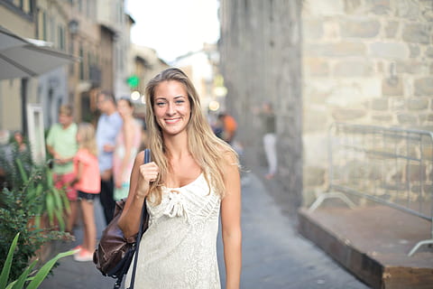 young, blonde, woman, white, dress, carrying, leather bag, posing, street, 25-30 year old, adult, lady, plant, portrait, stand, blurred background, building, carry, caucasian, fashion, female, leather, leaves, leisure, lifestyle, outdoor, people, pose, relax, road, smile, style, stylish, sunny, town, urban, walk, youth, young adult, city, smiling, architecture, young women, happiness, long hair, hairstyle, hair, beauty, beautiful woman, city life, one person, incidental people, emotion, looking at camera, women, city street, outdoors, 2K