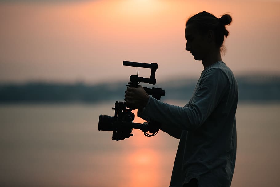 home que sosté la càmera, humà, persona, fotografia, arma, pistola, armament, fotògraf, foto, silueta, sol, càmera, home, riu, director de fotografia, cinima, home de la càmera, estabilitzar-se, cardanal, producció cinematogràfica, lent, posta de sol, una persona, cel, càmera - equip fotogràfic, temes de fotografia, naturalesa, celebració, tecnologia, persones reals, punteria, color taronja, vista lateral, trípode, homes, tres quarts de longitud, de peu, ocupació, vista del perfil, operador de càmera, 4K