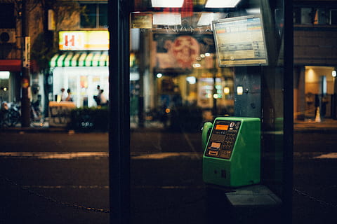 glass phonebooth, osaka, city, architecture, street, communication, night, illuminated, text, building exterior, incidental people, focus on foreground, outdoors, transportation, city life, built structure, western script, technology, city street, business, reflection, 5K, CC0, public domain, royalty free