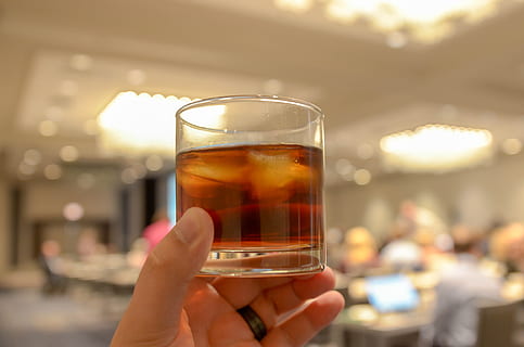 alcohol, whiskey, drink, ice, neat, beverage, glass, event, party, toast, liquor, luxury, restaurant, celebration, celebrate, refreshment, wine, bubbles, bokeh, hotel, convention, ring, band, rich, refined, human hand, hand, food and drink, human body part, holding, focus on foreground, household equipment, one person, drinking glass, lifestyles, close-up, adult, body part, real people, women, finger, drinking, 4K, CC0, public domain, royalty free