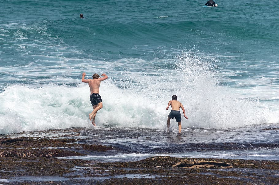 onades, nois, saltar, roques, oceà, aigua, mar, moviment, estils de vida, onada, activitat d'oci, persones reals, esport, dia, dues persones, naturalesa, homes, sense camisa, platja, gent, surf, escenics - natura, bellesa a la natura, esquitxades, a l'aire lliure, poder a la natura, 5K