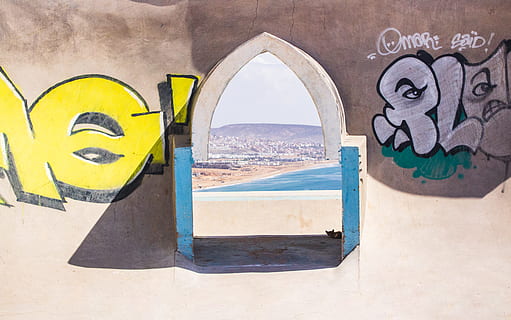 murale, manifesto, collage, taghazout, marocchino, bavaglino, etichetta, testo, arte, arte Moderna, graffiti, mobilia, tavolino da caffè, tavolo, bicchieri, emblema, architettura, struttura costruita, arte e artigianato, nessuno, giorno, creatività, acqua, natura, esterno dell'edificio, luce del sole, all'aperto, arco, rappresentazione, caratteristica della parete, terra, giallo, finestra, parete, 5K, CC0, dominio pubblico, privo di copyright