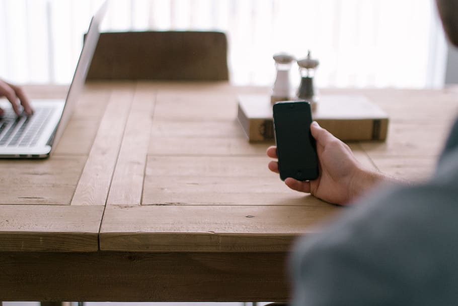 iphone, mà, home, treballar, MacBook, portàtil, tecnologia, negocis, fusta, taula, cadira, llibre, sal, pebre, reunió, tecnologia sense fils, comunicació, mà humana, part del cos humà, connexió, una persona, celebració, a l'interior, enfocament selectiu, ordinador, adult, dispositiu d’informació portàtil, telèfon intel·ligent, telèfon mòbil, comoditat, usant portàtil, 5K