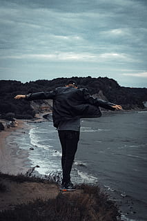 uomo, in piedi, scogliera, di fronte, corpo, acqua, luce del giorno, oceano, all'aperto, persona, mare, lunghezza intera, cielo, persone reali, una persona, nuvola - cielo, stili di vita, spiaggia, attività di svago, retrovisore, terra, bellezza nella natura, scenics - natura, natura, giorno, capi di abbigliamento, vestiti caldi, 5K, CC0, dominio pubblico, privo di copyright