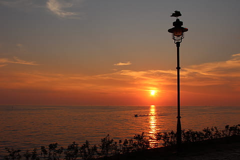 posta de sol, paisatge, mar, llanterna, cel, equips d’il·luminació, aigua, llum del carrer, carrer, escenics - natura, bellesa a la natura, núvol - cel, naturalesa, horitzó, escena tranquil·la, color taronja, horitzó sobre l’aigua, tranquil·litat, idíl·lic, cap gent, il·luminat, a l'aire lliure, sol, llum, llum elèctrica, 2K, CC0, domini públic, lliure de regalies