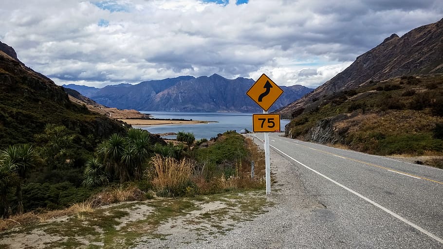senyalització de carreteres sinuoses, núvols, ennuvolat, la llum del dia, herba, paisatge, muntanya, carretera, senyal de trànsit, escènic, aigua, signe, cel, núvol - cel, Serra, escenics - natura, comunicació, bellesa a la natura, símbol, naturalesa, transport, direcció, el camí a seguir, escena tranquil·la, cap gent, tranquil·litat, escena no urbana, orientació, 4K