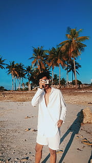 Mann, tragen, Weiß, Smokinghemd, kurze Hose, halten, grau, Kamera, Strand, Tageslicht, Spaß, Landschaft, Freizeit, draußen, Palme, Person, Fotografie, Erholung, Felsen, Sand, Schatten, Ufer, Sommer-, Sonne, Reise, tropisch, Urlaub, echte Menschen, eine Person, Land, Baum, Freizeitbeschäftigung, Vorderansicht, tropisches Klima, Himmel, Lebensstile, Sonnenlicht, junger Erwachsener, Natur, Pflanze, Stehen, Tag, junge Männer, Legere Kleidung, reife Männer, 4K, CC0, gemeinfrei, lizenzfrei