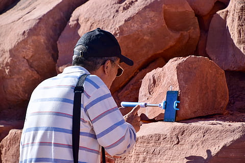 Borsa, berretto, cappello, uomo, smartphone, tempo di affrontare, chat, persona, rocce, bastone selfie, striscia superiore, occhiali da sole, parlando, pietre, asciutto, polveroso, dito d'ondeggiamento, roccia - oggetto, roccia, persone reali, solido, formazione rocciosa, persone, stili di vita, attività di svago, natura, adulto, luce del sole, vista laterale, giorno, donne, all'aperto, dalla vita in su, abbigliamento casual, adulto maturo, archeologia, 4K, CC0, dominio pubblico, privo di copyright