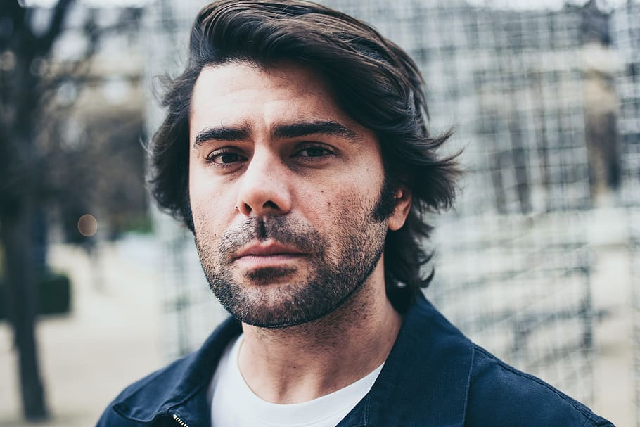 la cara de l'home, cara, persona, humà, barba, home, retrat, foto, fotografia, intèrpret, cabell, gent, tall de cabell, pell, arrufar les celles, somriu, abric, jaqueta, roba, cap, tirada al cap, una persona, home jove, persones reals, adult jove, mirant la càmera, centrar-se en primer pla, vista frontal, pèl facial, estils de vida, arquitectura, homes, dia, rostoll, primer pla, a l'aire lliure, contemplació, rostre humà, 5K