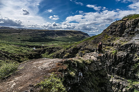 person, bjergklint, klipper, skyer, dagslys, miljø, græs, høj, landskab, bjerge, natur, naturfotografering, udendørs, naturskøn, syn, sidder, kvinde, sky - himmel, bjerg, skønhed i naturen, scenics - natur, ikke-urbane scene, fritidsaktivitet, klippe, rigtige mennesker, dag, solid, rock-objekt, himmel, livsstil, ro, en person, rock formation, rolig scene, bjergkæde, formation, 2K, CC0, offentligt domæne, royaltyfrie