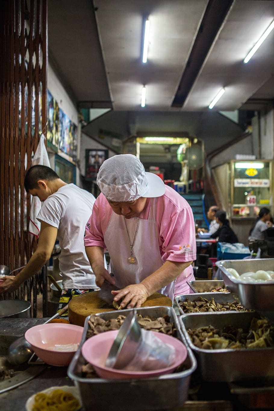 Kunst, Widmung, Fertigkeit, Stall, Lebensmittel, Straße, Koch, Dame, Frau, China Town, Thailand, Bangkok, Essen und Trinken, Erwachsene, Arbeiten, Geschäft, Vorbereitung, Frische, Besetzung, echte Menschen, Stehen, Menschen, zufällige Menschen, drinnen, Lebensmittel- und Getränkeindustrie, beleuchtet, Männer, Restaurant, Markt, Fleisch, Essen vorbereiten, 5K