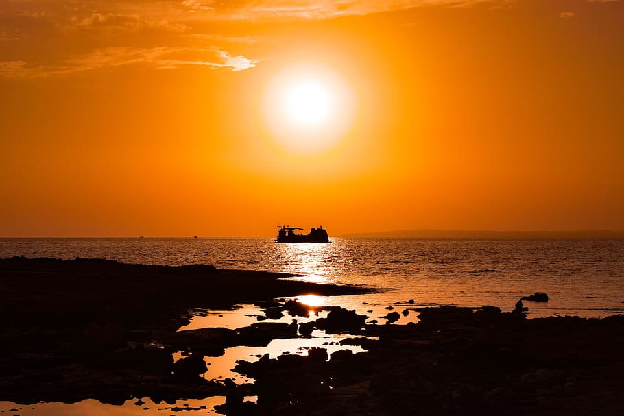 posta de sol, costa rocosa, sol, vaixell, horitzó, mar, silueta, escumós, llum solar, taronja, naturalesa, vespre, tarda, ayia napa, aigua, cel, color taronja, escenics - natura, bellesa a la natura, horitzó sobre l’aigua, vaixell nàutic, reflexió, transport, tranquil·litat, manera de transport, escena tranquil·la, cap gent, a l'aire lliure, brillant, veler, embarcacions de passatgers, 5K