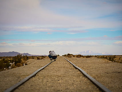 person kigger ned, Bolivia, person, Uyuni, grus, vej, grusvej, spore, krybe sammen, udendørs, himmel, Sky, togspor, jernbane, bjerg, horisont, ørken, kameratelefon, rejse, udforske, sky - himmel, en person, bagfra, rigtige mennesker, natur, scenics - natur, transportmidler, dag, jernbanetransport, miljø, fritidsaktivitet, landskab, retning, vejen frem, livsstil, fuld længde, jernbanespor, faldende perspektiv, 5K, CC0, offentligt domæne, royaltyfrie