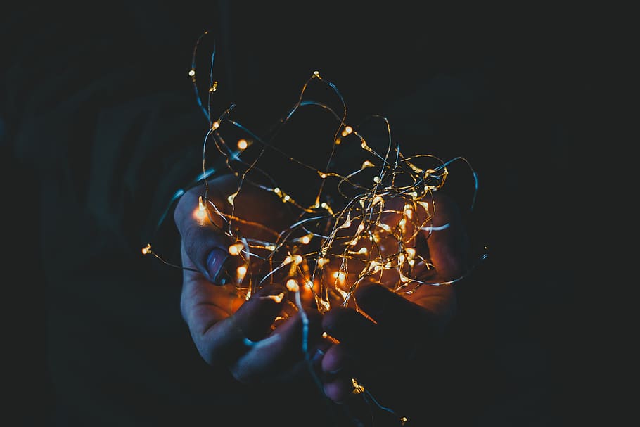 persona, detenzione, luci di stringa, luce, luce natalizia, luci fatate, splendore, illuminato, buio, mano, scintillante, Natale, conifera, albero, pianta, flora, fuoco, illuminazione, luci di Natale, luci, mani, mano umana, una persona, parte del corpo umano, in casa, sfondo nero, avvicinamento, parte del corpo, tecnologia, persona irriconoscibile, ardente, girato in studio, natura, lunga esposizione, arto, comunicazione, movimento, arto umano, dito, 5K