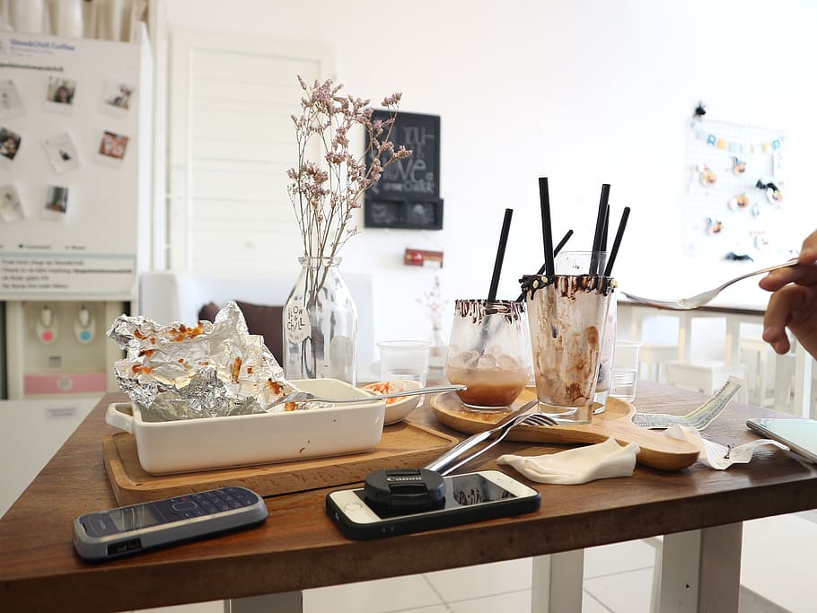 buit, gots, plaques, taula, mòbil, menjar, taula de menjador, acabat, paper d'alumini, forquilla, mà, a l'interior, endins, estris de cuina, restaurant, habitació, seient, smartphone, palla, vaixella, tecnologia, gerro, menjar i beguda, una persona, raspall, pinzell, estri de cuina, mà humana, tecnologia sense fils, dia, utensili per menjar, centrar-se en primer pla, contenidor, celebració, part del cos humà, material de fusta, interior de casa, safata, 4K