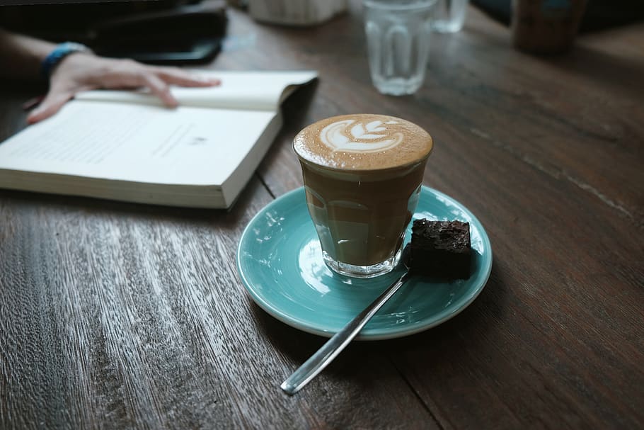 llegir, llibre, lectura, llibre de lectura, sol, cafè, brownie, cafè amb llet, contenidor de ceràmica, cafeteria, latte, espresso, to fosc, fons de pantalla, fons, solitari, setmanal, beguda calenta, beure, taula, cafè - beguda, tassa de cafè, menjar i beguda, tassa, refresc, beguda espumosa, plat, a l'interior, natura morta, material de fusta, vaixella, centrar-se en primer pla, cullera, cappuccino, mà, vidre, 2K