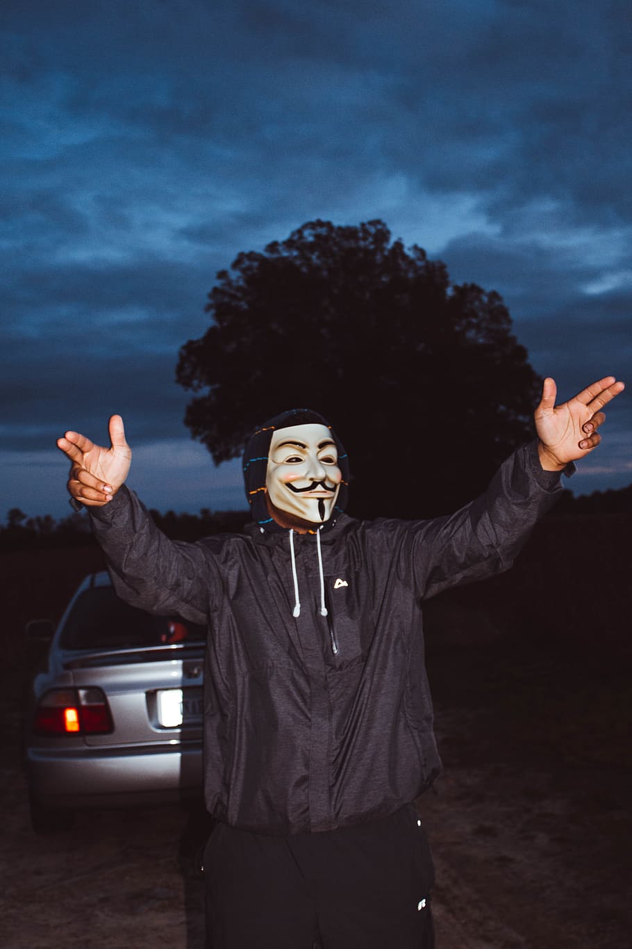 foto, persona, portar, màscara, noi, alba, gest, paio, mascle fawkes tipus, mans, dessuadora, jaqueta, masculí, home, pose, postura, desgast, braç humà, gesticulant, membre, una persona, vista frontal, de peu, braços aixecats, tres quarts de longitud, emoció, cotxe, adult jove, braços estesos, cel, persones reals, felicitat, transport, mirant la càmera, automòbil, extremitat humana, a l'aire lliure, 5K