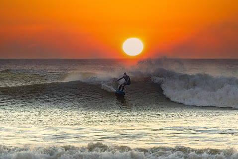 mand leger surfer, hav, vand, himmel, bølge, bevægelse, solnedgang, horisont over vand, horisont, natur, surfing, orange farve, sport, vandsport, skønhed i naturen, mennesker, scenics - natur, strøm, udendørs, magt i naturen, 5K, CC0, offentligt domæne, royaltyfrie