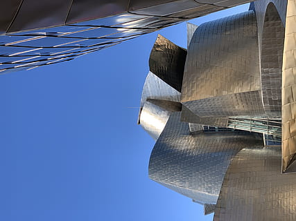 edifici de formigó gris, edifici, arquitectura, edifici d'oficines, abandoibarra etorb., espanya, bilbo, ciutat, urbà, metròpolis, museu, centre de la ciutat, centre de Convencions, guggenheim, bilbao, titani, multitud, pont, torre, observatori, cel, blau, estructura construïda, dia, naturalesa, vista d’angle baix, cel clar, exterior de l'edifici, cap gent, llum solar, modern, destinacions de viatge, a l'aire lliure, viatjar, religió, directament a sota, gratacels, 4K, CC0, domini públic, lliure de regalies