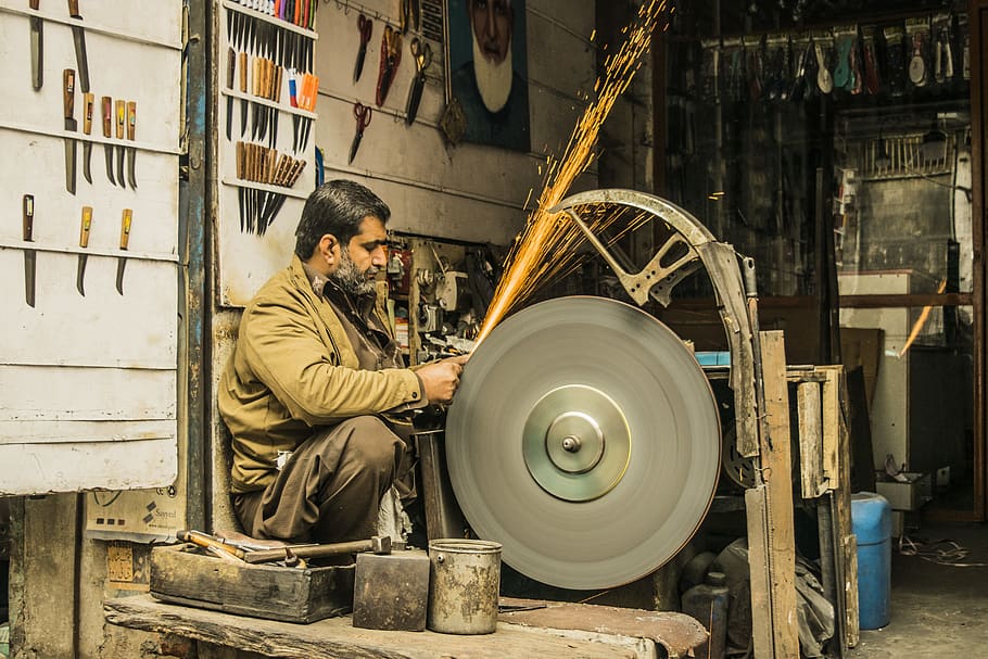 uomo, affilatura, strumento, grigio, macchina, dentro, camera, una persona, occupazione, persone reali, lavoro, uomini, industria, abilità, laboratorio, in casa, macchinario, adulto, seduta, attività commerciale, fabbrica, competenza, architettura, metallo, concentrazione, industria dei metalli, scintille, ruota, 5K