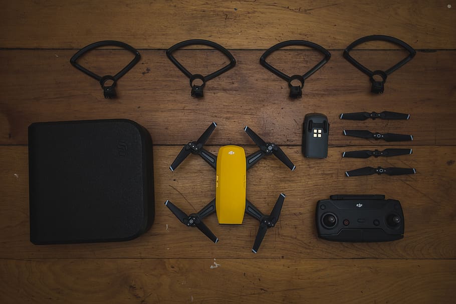 dji, espurna, drone, uav, quadcopter, multirotor, aèria, càmera, hèlix, fusta, taula, producte, despeses generals, groc, petit, bateria, guàrdia de suport, remot, a l'interior, eina de treball, material de fusta, natura morta, directament a sobre, cap gent, tisores, equipament, arranjament, gots, gran grup d'objectes, vista d’angle alt, elecció, metall, grup d'objectes, variació, tecnologia, ulleres, tecnologia sense fils, ordre, 5K