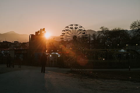 flamarada, llum, humà, persona, llum solar, Parc d'atraccions, roda de ferris, a l'aire lliure, sortida del sol, cel, naturalesa, metròpolis, urbà, edifici, ciutat, silueta, cel vermell, alba, posta de sol, passeig pel parc d’atraccions, arquitectura, estructura construïda, cultura i entreteniment artístic, exterior de l'edifici, sol, persones incidentals, flare de la lent, color taronja, arbre, activitat d'oci, recinte firal, brillant, 4K, CC0, domini públic, lliure de regalies