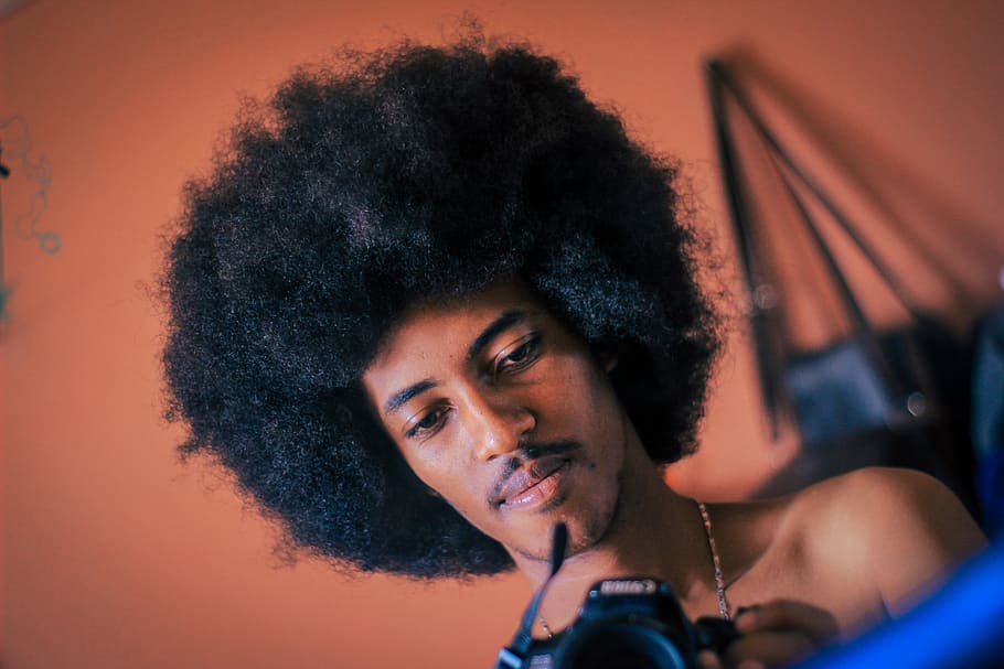 home que sosté la càmera, cabell, pentinat afro, persona, humà, gent, cara, cabell arrissat, retrat, una persona, tirada al cap, afro, adult jove, tecnologia, música, pentinat, adult, cultura i entreteniment artístic, a l'interior, bellesa, músic, ocupació, dona guapa, 5K
