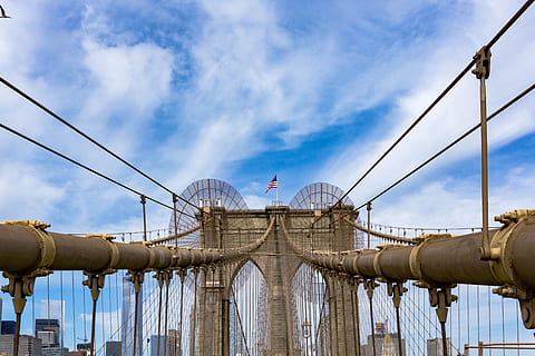 pont de Brooklyn, nou, York, arquitectura, pont, edifici, núvols, equipament, bandera, referència, tir en angle baix, new york, nova York, a l'aire lliure, cel, acer, Pont en suspensió, viatjar, núvol - cel, estructura construïda, naturalesa, connexió, vista d’angle baix, dia, transport, cap gent, ciutat, exterior de l'edifici, destinacions de viatge, blau, indústria, negocis, cable, 5K, CC0, domini públic, lliure de regalies