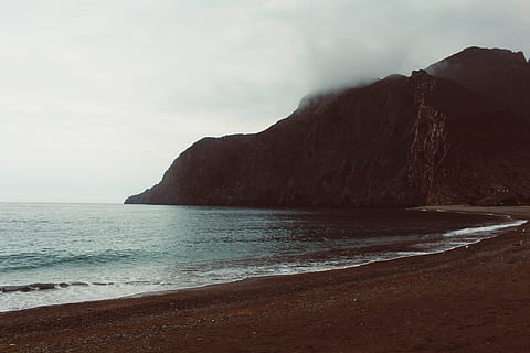 muntanya propera a la vora del mar, platja, núvols, alba, la llum del dia, boira, illa, paisatge, muntanya, oceà, a l'aire lliure, sorra, escènic, mar, vora del mar, cel, posta de sol, viatjar, aigua, onades, terra, bellesa a la natura, escenics - natura, escena tranquil·la, tranquil·litat, rock, naturalesa, horitzó sobre l’aigua, rock - object, horitzó, cap gent, penya-segat, sòlid, núvol - cel, 5K, CC0, domini públic, lliure de regalies