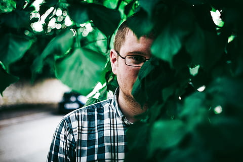man, eyeglasses, standing, behind, green, leaves, boy, guy, hiding, person, one person, green color, focus on foreground, real people, headshot, men, portrait, adult, casual clothing, mid adult men, lifestyles, mid adult, day, nature, plant, looking, checked pattern, plant part, leisure activity, outdoors, 5K, CC0, public domain, royalty free