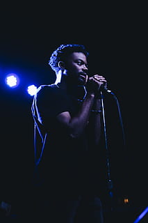 uomo, in piedi, detenzione, microfono, dispositivo di input, cantando, una persona, stage - spazio per le prestazioni, cantante, prestazione, cultura artistica e intrattenimento, palcoscenico, musica, dalla vita in su, notte, illuminato, musicista, giovane adulto, in casa, evento artistico, vista frontale, girato in studio, luce, supporto per microfono, luce scenica, sfondo nero, concerto, vita notturna, 5K, CC0, dominio pubblico, privo di copyright