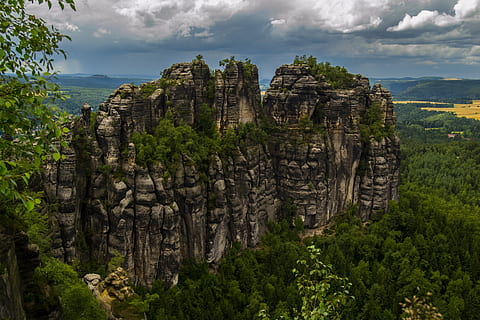 rock formation, surrounded, green, trees, humid, weather, cliff, clouds, cloudy, conifers, dark clouds, fir trees, forest, landscape, mountains, nature, pine trees, rock formations, rocks, sky, storm, woods, cloud - sky, plant, tree, land, travel destinations, no people, architecture, environment, beauty in nature, rock, mountain, built structure, solid, tourism, scenics - nature, travel, outdoors, ancient civilization, 1080P, CC0, public domain, royalty free