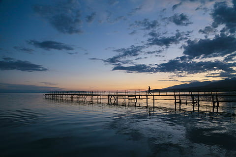 foto, persona, caminar, moll, platja, pont, núvols, alba, medi ambient, idíl·lic, embarcador, naturalesa, oceà, pacífica, ondulacions, paisatge, escènic, mar, paisatge marí, vora del mar, cel, sortida del sol, posta de sol, tranquil, aigua, núvol - cel, escenics - natura, bellesa a la natura, escena tranquil·la, tranquil·litat, reflexió, arquitectura, davant del mar, estructura construïda, escena no urbana, color taronja, a l'aire lliure, cap gent, post de fusta, 5K, CC0, domini públic, lliure de regalies