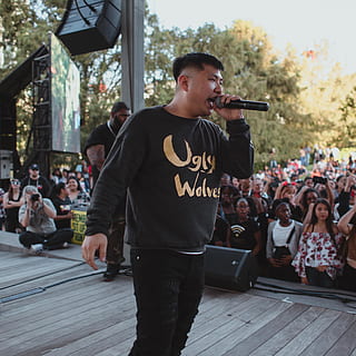 man, talking, using, microphone, stage, person, human, interior design, indoors, audience, crowd, apparel, clothing, skin, sleeve, leisure activities, building, bridge, boardwalk, people, cap, hat, long sleeve, pedestrian, musical instrument, real people, lifestyles, group of people, men, casual clothing, performance, event, standing, leisure activity, music, incidental people, architecture, arts culture and entertainment, focus on foreground, looking, young men, teenager, 4K, CC0, public domain, royalty free